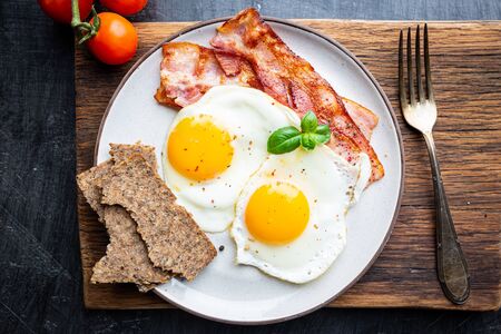 Fried eggs and bacon for breakfast on a plate, top view, copyspaceの写真素材