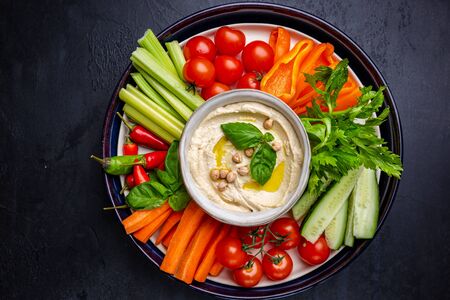 Hummus platter with assorted snacks. Hummus in bowl and vegetables sticks.