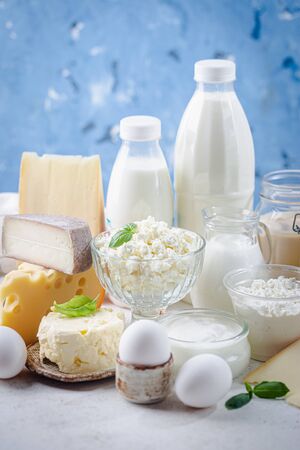 Fresh dairy products, milk, cottage cheese, eggs, yogurt, sour cream and butter on blue backgroundの写真素材
