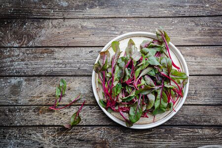 Fresh mangold leaves in the plate on rustic wooden background. Top viewの写真素材