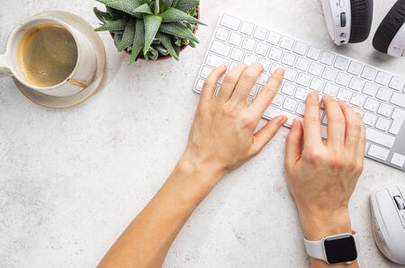 Flat lay or top view office table desk. Workspace with blank, keyboard, with girls hands green plant...