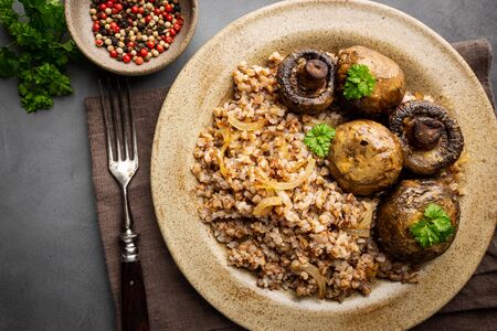 Buckwheat porridge with mushrooms in a plate on black background, top viewの写真素材