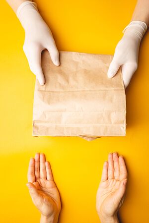 contactless delivery concept, gloved hands transmit the package with corona virus protect. Safe courier deliveryの写真素材