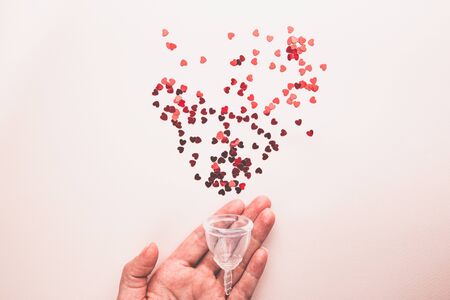 Menstrual cup on pink background. Alternative environmentally friendly feminine hygiene product to collect blood during the period inside the vagina.の写真素材