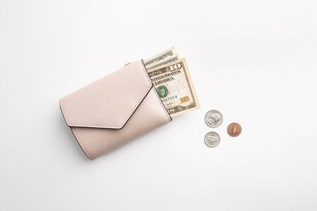 Beautiful leather pink wallet with coins laying on white paper background, top view