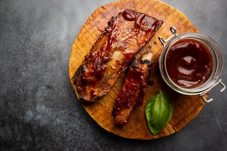 Delicious BBQ baby-back ribs with tangy sauce and a basting brush on black background, top viewの写真素材