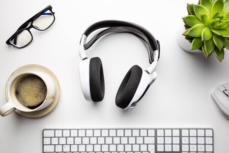 Home office desk workspace with Headphones, glasses, coffee and keyboard on white background, top view, flat layの写真素材
