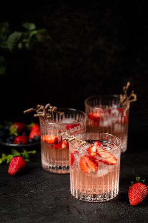 Refreshing summer drink with strawberry slices in glasses on black backgroundの写真素材