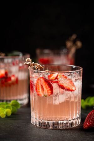 Refreshing summer drink with strawberry slices in glasses on black backgroundの写真素材