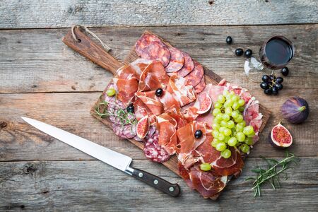 Sliced jamon on cutting board with figÑ, grapes and red wine. Parma ham / hamon on wooden background with copy space, top view. Jamon Serrano / Iberico. Traditional Spanish hamの写真素材