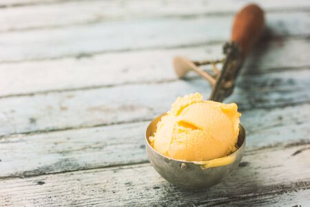 Homemade mango ice cream in a bowls with fresh fruits over white wooden background.の写真素材