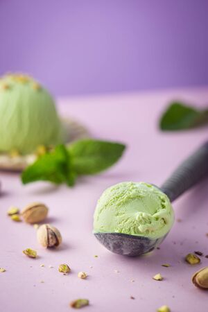 Homemade pistachio ice cream with chopped pistachios on bright pink and purple backgroundの写真素材