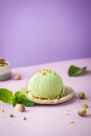 Homemade pistachio ice cream with chopped pistachios on bright pink and purple backgroundの写真素材