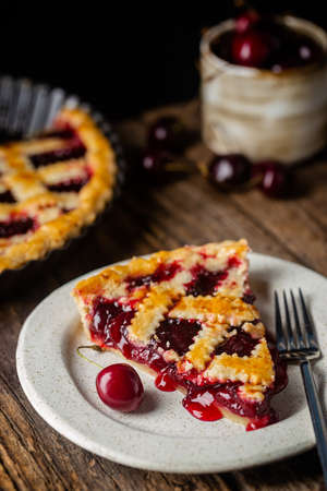 piece of Delicious homemade classic cherry pie with a flaky crust on dark rustic backgroundの写真素材