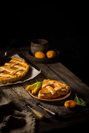 Summer homemade apricot or peach pie on dark wooden background. Delicious fruit dessert. Fruit cake.の写真素材