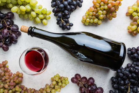 Red wine in a glass and ripe grapes on gray background, top viewの写真素材