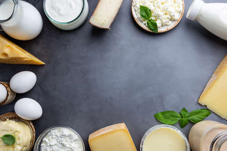 Fresh dairy products, milk, cottage cheese, eggs, yogurt, sour cream and butter on black background, top viewの写真素材