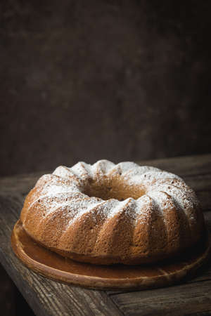 Rustic Style Apple Bundt Cake Sprinkled with Icing Sugar on old wooden table