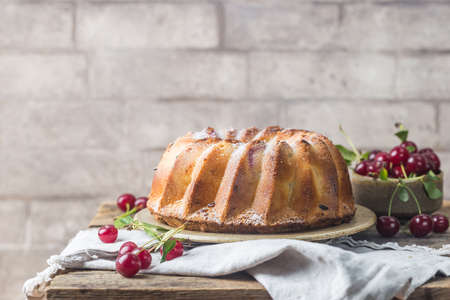 Fresh homemade bundt cake with cherry on wooden tableの写真素材