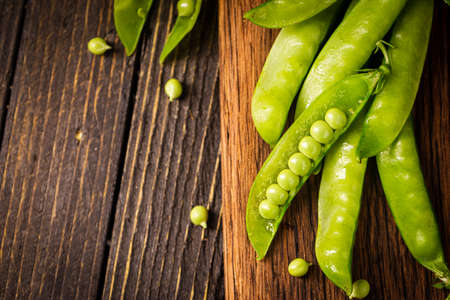 Pods of green peas on a old wooden background close up, soft focusの写真素材