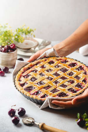 Delicious homemade classic cherry pie with a flaky crust in a womens hands on white backgroundの写真素材