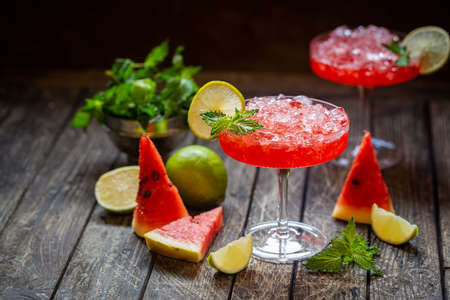 Watermelon frozen cocktail margarita with fresh watermelon, lime and mint on wooden backgroundの写真素材