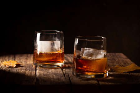 Glass of scotch whiskey and ice on wooden backgroundの写真素材