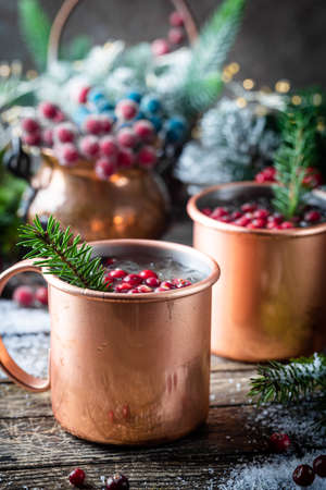 Mulled wine with cranberry in copper mug with christmas decorations on wooden tableの写真素材