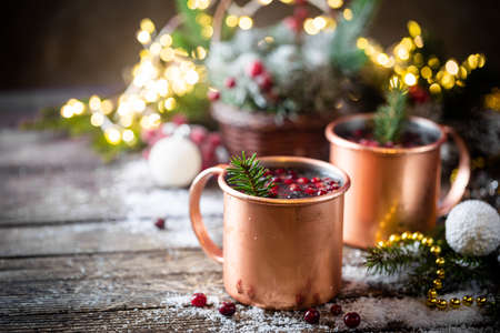 Mulled wine with cranberry in copper mug with christmas decorations on wooden tableの写真素材