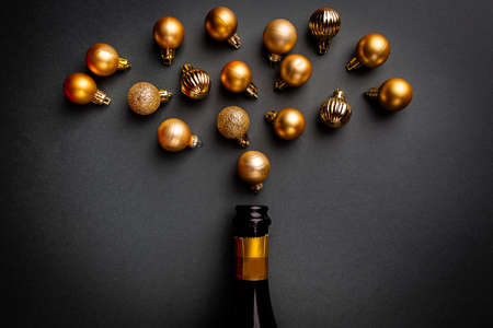 Champagne bottle with gold christmas balls on black background. Flat lay, top view, trendy christmas concept.の写真素材