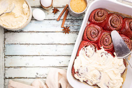 Homemade cinnamon rolls red velvet with cream cheese glaze on white wooden background, top viewの写真素材