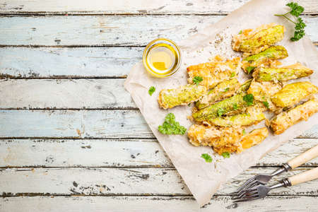 Zucchini sticks in batter, baked in oven over wooden background, top viewの写真素材