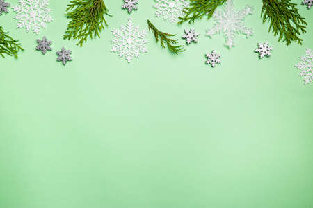 Christmas composition made of snowflakes and thuja branches on green background, top view. Winter...