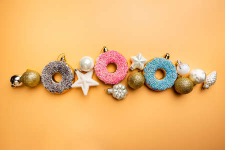 Christmas banner with toy glazed donut and christmas decorations, top view. Orange pastel...