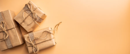 Christmas gift or present box wrapped in kraft paper with decoration on gold or champagne background, top view with copy spaceの写真素材