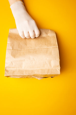 contactless delivery concept, gloved hands transmit the package with corona virus protect. Safe courier deliveryの写真素材