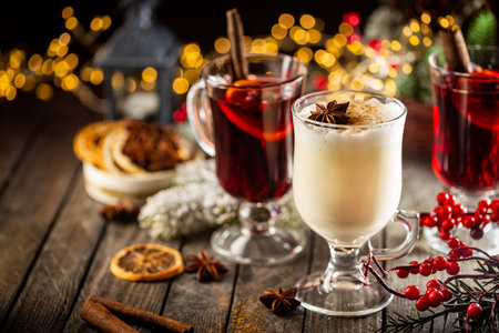 fresh yellow eggnog and fruity red mulled wine with Christmas decoration. Selection of autumn or winter alcoholic hot drinksの写真素材