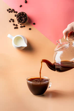 pouring coffee in a cup creating splashes with ingredients on colorful orange and pink backgroundの写真素材