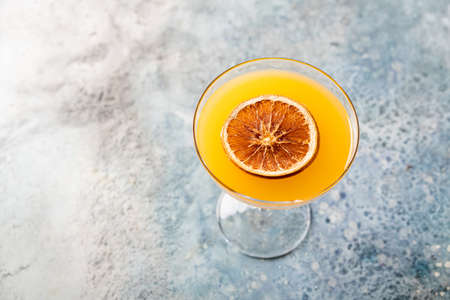 Fresh tall glass of tropical cocktail with rum and orange juice garnished with dry orange