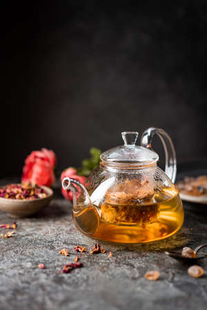 herbal flower tea from the petals of rose in a glass teapot on dark gray backgroundの写真素材