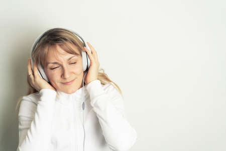 Portrait of smiling pretty woman enjoying music with white headphones on white background