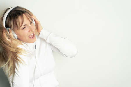 Portrait of smiling pretty woman enjoying music with white headphones on white background
