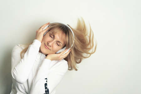 Portrait of smiling pretty woman enjoying music with white headphones on white backgroundの写真素材