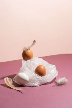 Brown eggs in cellophane on pastel pink background. modern concept of minimalism