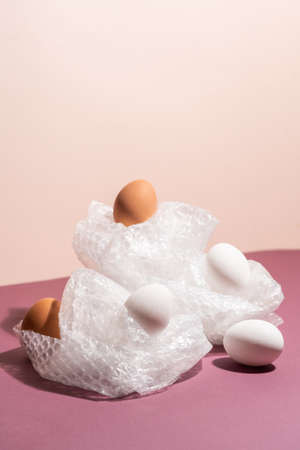 Brown eggs in cellophane on pastel pink background. modern concept of minimalismの写真素材