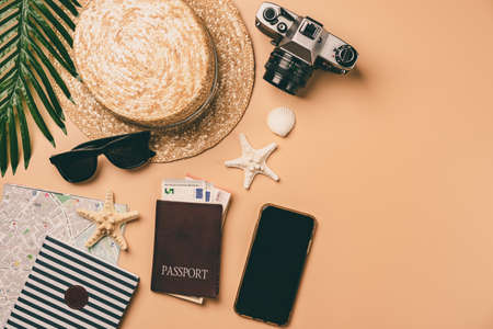 Top view travel concept with retro camera films, map and passport on light orange background with copy space. Flat lay tourist essentialsの写真素材