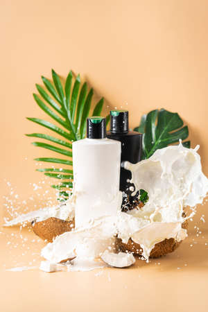 Bottle of hair shampoo and fresh organic coconut , natural cosmetic on light orange backgroundの写真素材