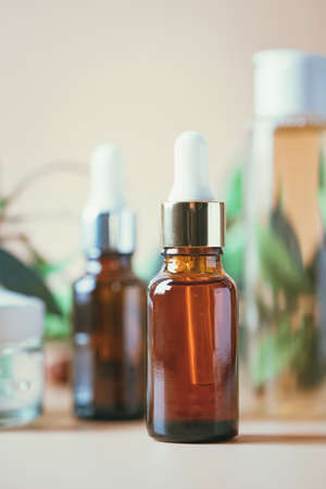 Olive based cosmetic serum, cream and water with sprig of olives on a pastel background