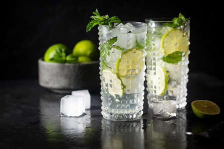 Glass of iced lemonade with lime and mint, cold summer drink on dark backgroundの写真素材