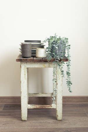 Old chair with authentic handmade ceramic dishes, plants and plates in empty room.